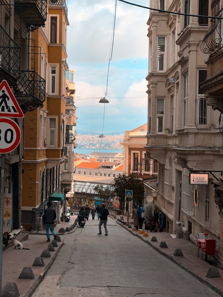 a narrow city street with people walking down it